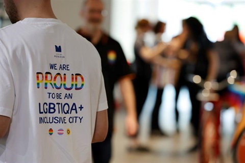 A person wearing a white T-shirt with the words 'We are proud to be an LGBTIQA+ inclusive city' on the back