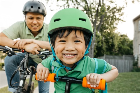 Young child in helmet on scooter 