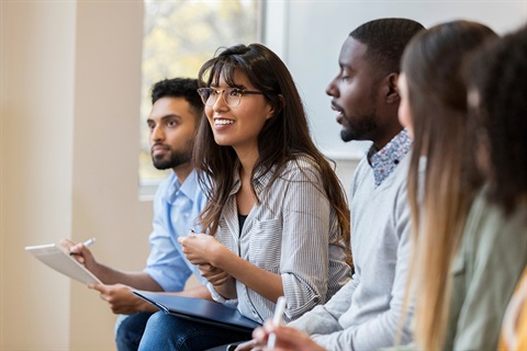 A young woman speaking up in a group brainstorm