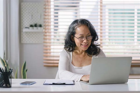 Older Asian lady using her laptop at home