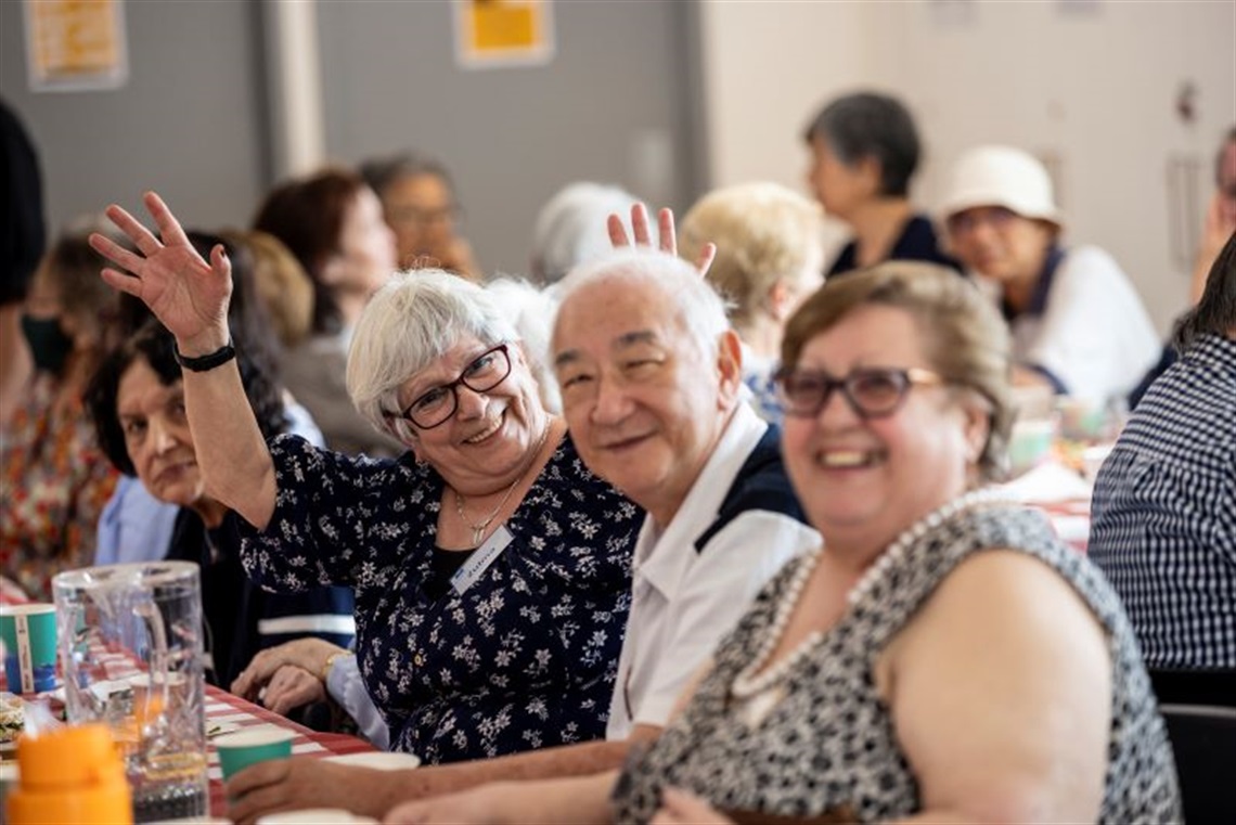 A group of smiling seniors sitting together at Monash Seniors Festival Notting Hill Neighbourhood House community lunch