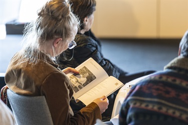 Audience member reading Poetic Portraits book at launch