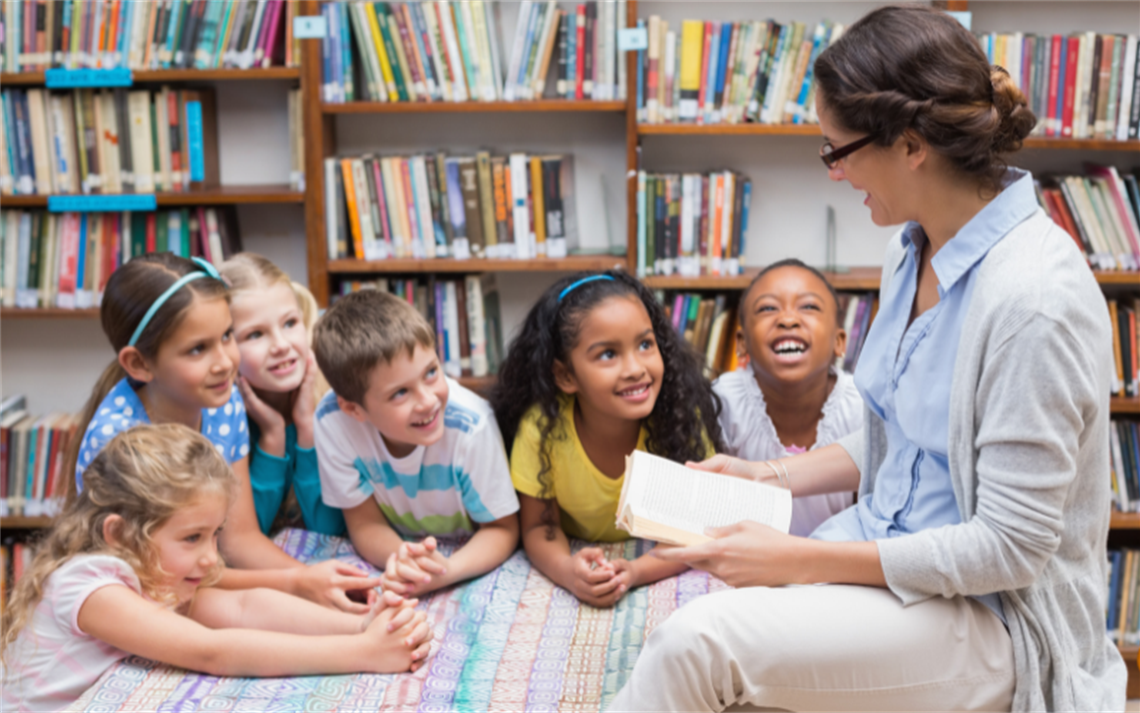 A teacher reading to a group of pupils in a library
