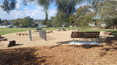 Dog off-leash area at Whitehaven Crescent Reserve in July 2026, with logs, boulders, ramp and bench seat for dog owners