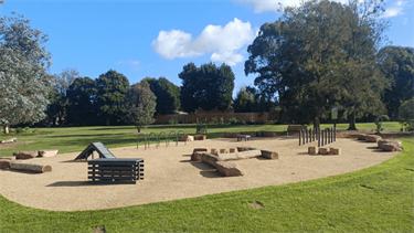 Dog off-leash area at Whitehaven Crescent Reserve in July 2026, with logs, agility hoops, boulders, ramp and more enrichment equipment