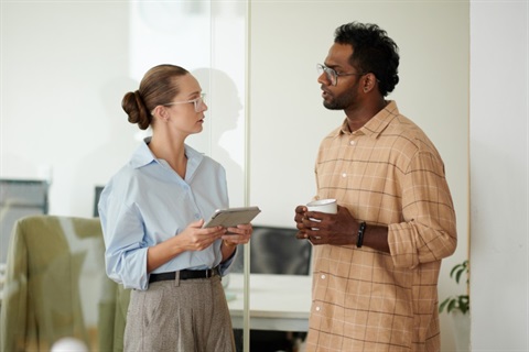 2 business professionals taking a break and talking to each other in front of in a modern office