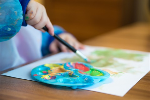 child with an art smock on painting on paper